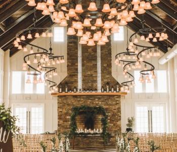 Zikloi 30LT Chandelier by 2nd Ave Lighting cascading down above a wedding venue and fireplace. Reminiscent of bell-shaped pink flowers.
