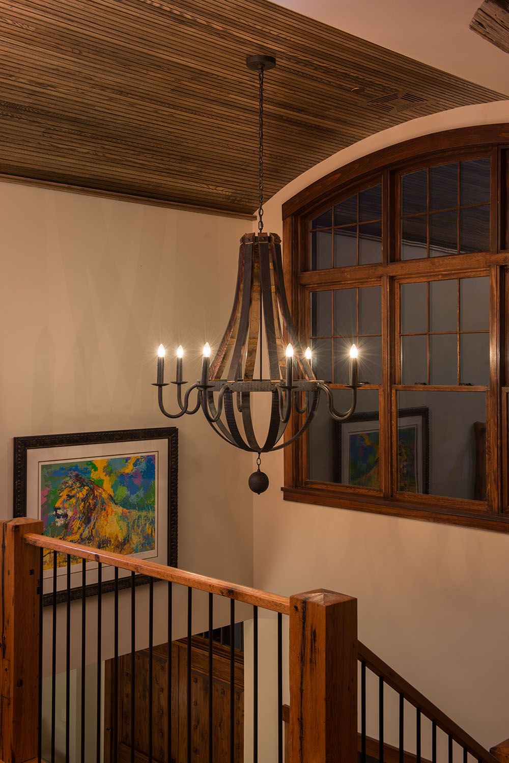 A 48"W Barrel Stave 8 LT Chandelier hanging above a wooden staircase.
